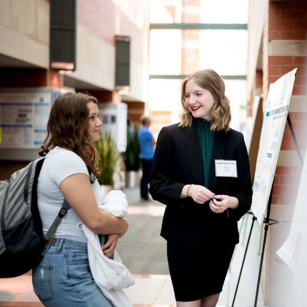 A student discusses her research with another student during Student Scholars Day