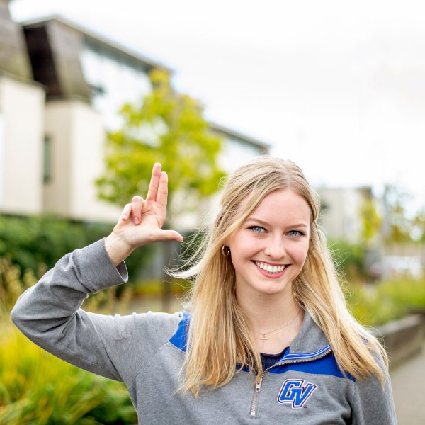 A student smiles while making the "Anchor Up" sign.