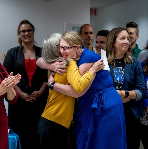 two women hugging, others stand behind them