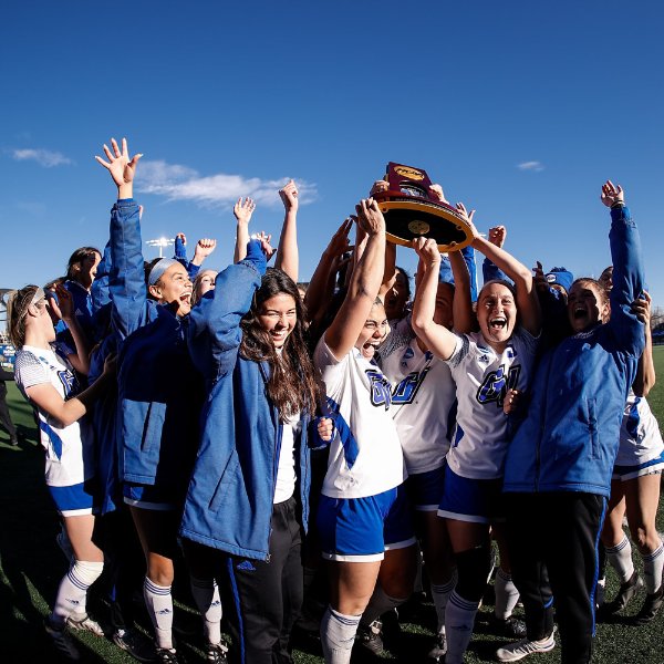 Soccer players lift trophy over their heads in celebration.