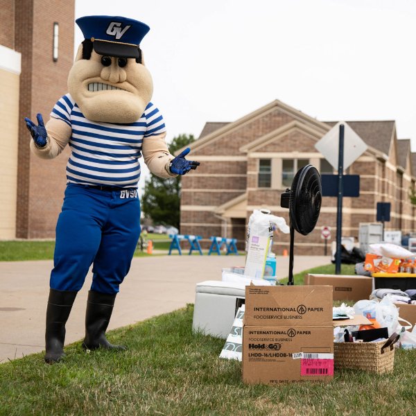 Louie the Laker stands next to boxes at move-in.