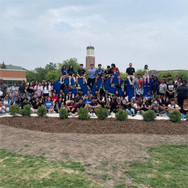 large group of students, staff sitting and standing near the GVSU letters