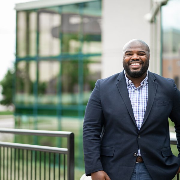 Edward Jones II standing in shirt and jacket outside the fieldhouse with one hand in pocket