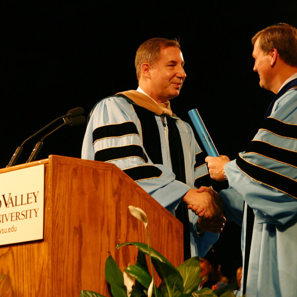 two presidents of Grand Valley in regalia with a baton