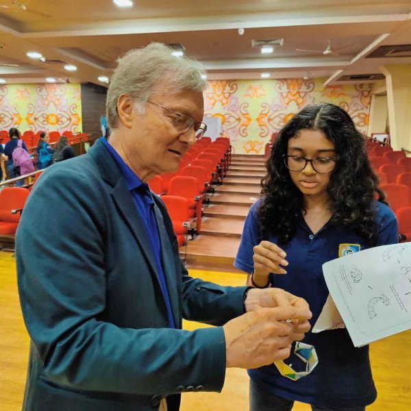 Mark Staves shows a dna piece of paper to a student in a classroom in India