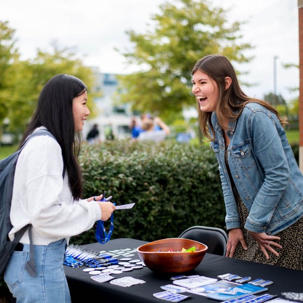 A woman speaks to a student over a table covered in small hand-outs.