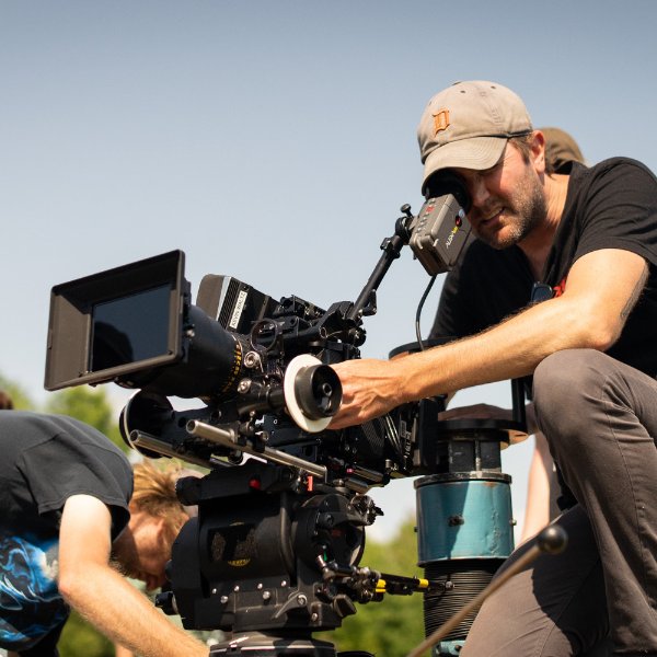 A person looks through a camera while filming a scene.