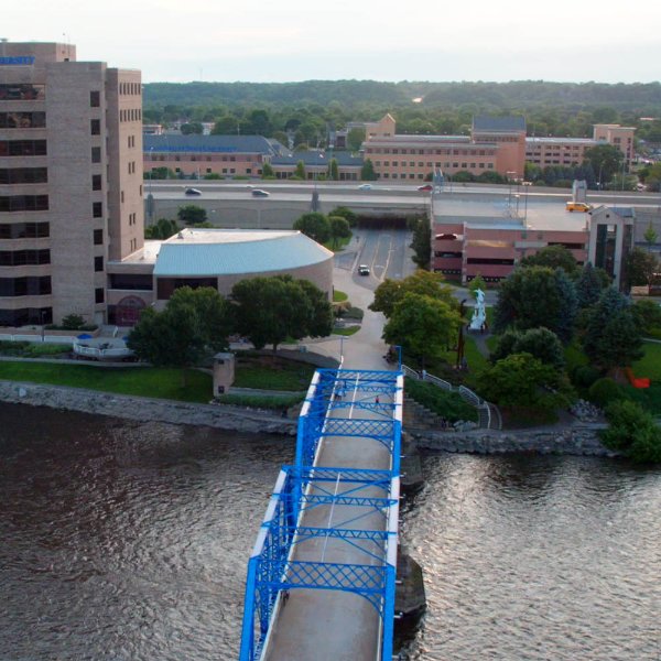 A blue bridge spans a river and connects to the campus area.