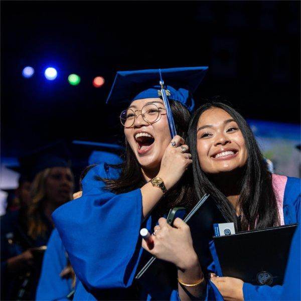 Two graduates react with joy after receiving their diplomas.