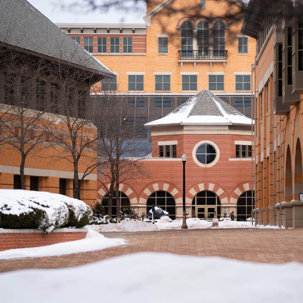 Different wings of a building is shown with a brick pathway and some snow.