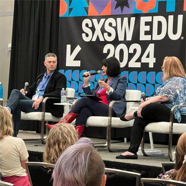 President Mantella sits on a stage between other panelists and speaks into a microphone.
