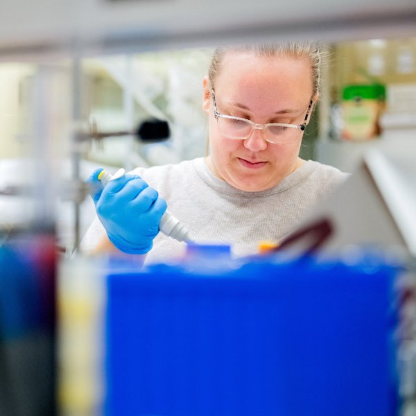 A person wearing safety goggles works in a lab.