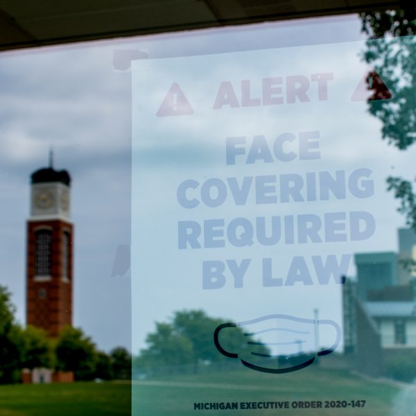 door sign that reads face coverings required by law