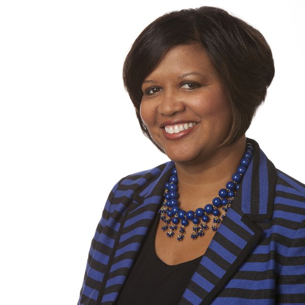 headshot of Tia Brown McNair, in blue and black striped jacket with blue beaded necklace, seated portrait