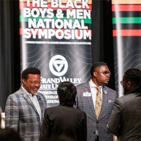 people standing at front of room before vertical banner, Black Boys and Men National Symposium