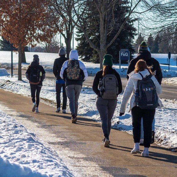 students walking with backs to the camera on sidewalk
