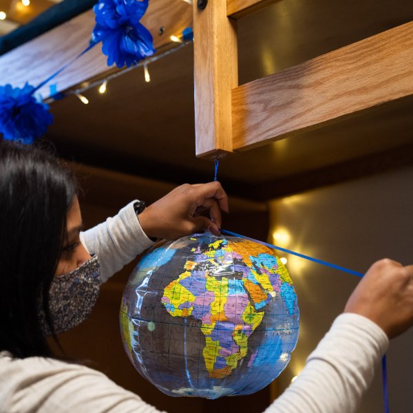 A GVSU employee hangs a globe in a campus residence hall.
