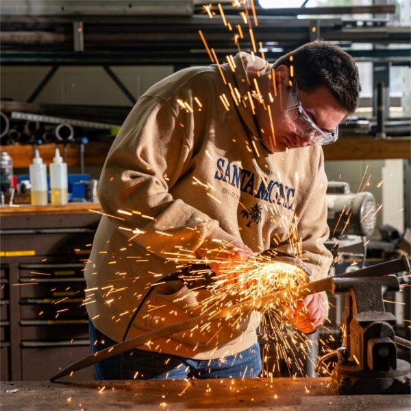 Sparks fly as mechanical engineering major Scott Strayer grinds a sword for a video crew at the Kennedy Hall of Engineering