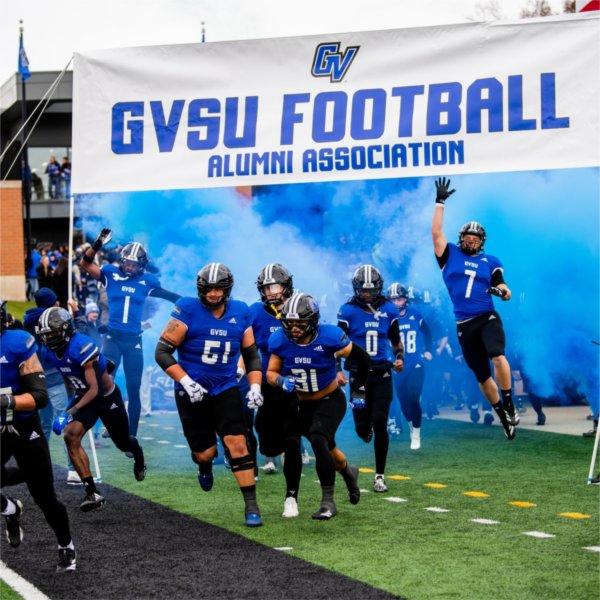 Football players enter the field for the Homecoming game.