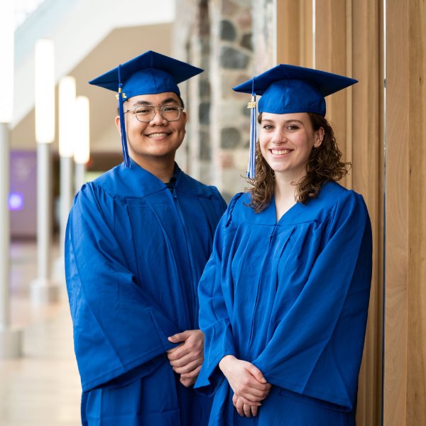 Long Ho and Grace Pallissard pose in academic regalia