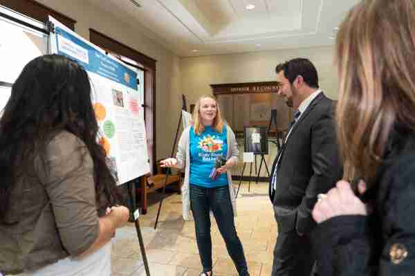 At right, Travus Burton, director for Civic Learning and Community Engagement, looks at a poster presentation from the 2019 Civic Engagement Showcase.