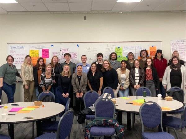 large group of people standing in two rows in front of a whiteboard