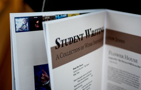 Part of a magazine is seen. Some images from Elton John albums are behind the page. At the foreground, the headline says, "Student Writing" and describes the content as a collection of work.