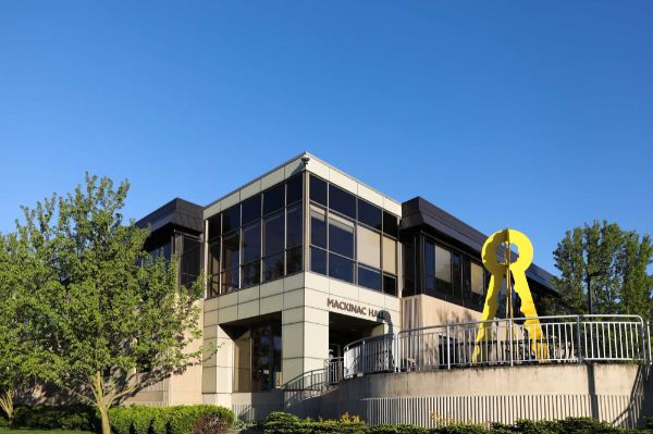 The entrance to a building with the words Mackinac Hall over the entrance. A yellow art sculpture is near the entrance.