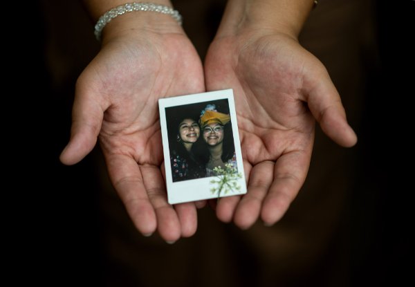 A Polaroid photo of two smiling sisters is held in a person's hands. 