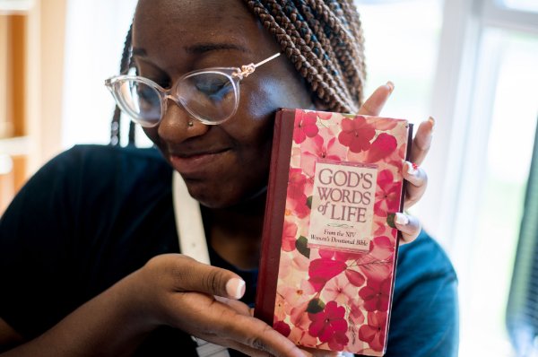  A college student wearing glasses holds a women's devotional bible. 