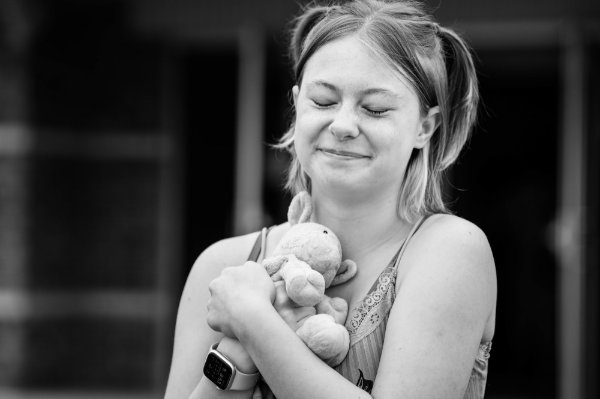 A college student hugs a stuffed animal during move-in. 