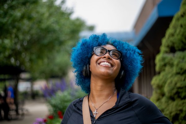  A young college student with blue hair smiles. 