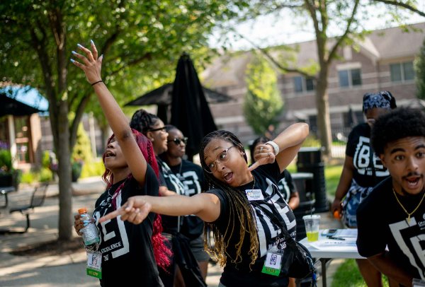  College students dance together in an outdoor commons area. 