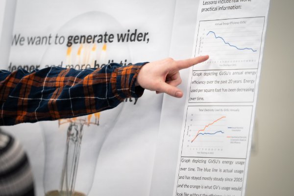 A person's arm, covered with a plaid shirt, is seen as the person points to information on a research board.