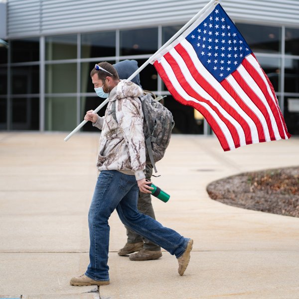 A veteran holds a U.S. flag while participating in a Veteran's Day hike in 2020.