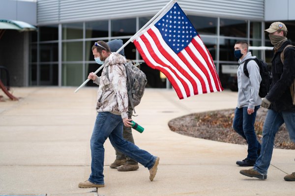 A veteran walks with the U.S. flag on a Veteran's Day hike in 2020.
