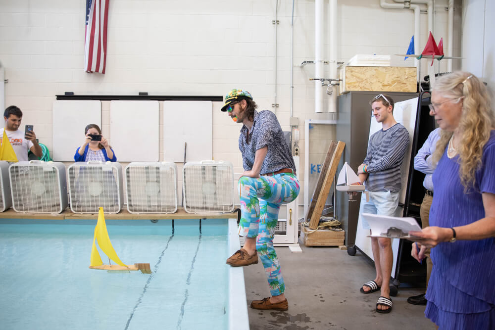 An engineering student, dressed for the regatta in a captain's hat and nautical-themed pants, watches his boat cross the test tank.