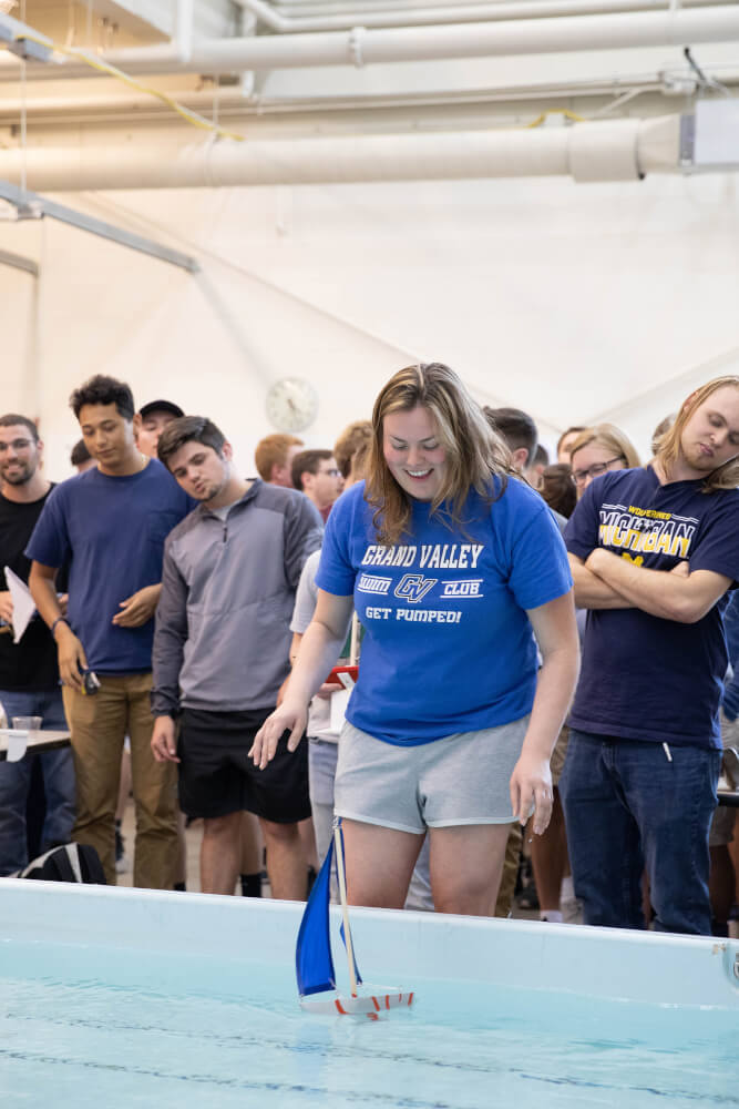 A student launches her boat into the test tank.