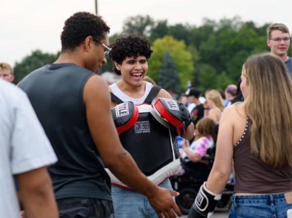 Gustavo Alonzo, a junior majoring in finance and member of the GVSU Boxing Club, laughs while encouraging a student to try out boxing gloves during Campus Life Night on August 30. 