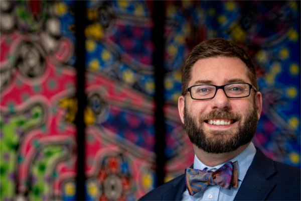 Kyle Kooyers in front of colorful artwork that is reflected in his bow tie