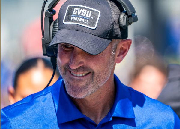 Head football coach Scott Wooster smiles on the sidelines during a Lakers game. 