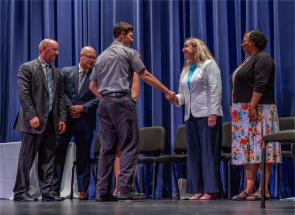 Graduate Colin Wojczynski is congratulated by Gretchen Galloway from the Michigan Commission on Law Enforcement Standards (MCOLES) during the Police Academy Graduation Ceremony at the Louis Armstrong Theatre on August 21.