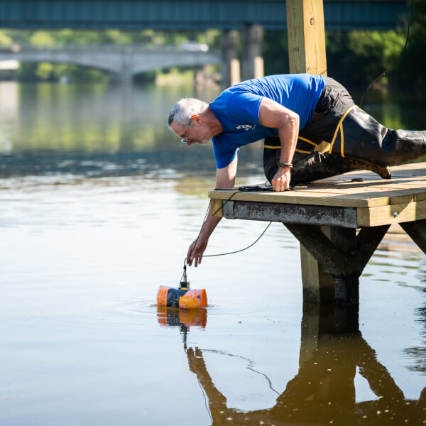 Peter Wampler, professor of geology, collects a sample from the Grand River.