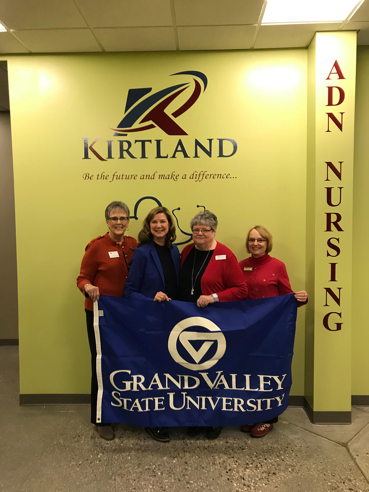 four women holding GVSU flag