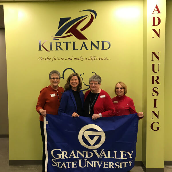 four women holding GVSU flag