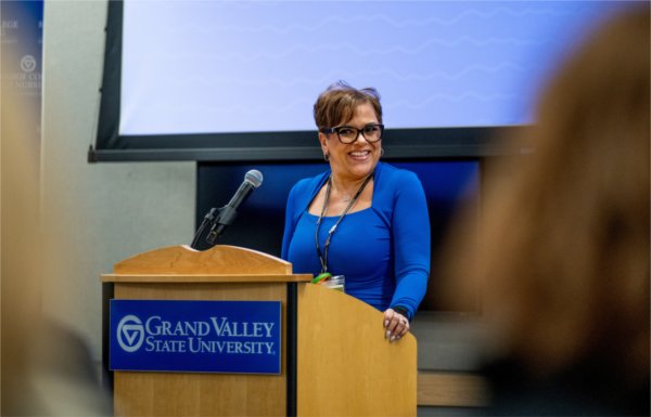 Lisette Wilson stands behind a GVSU podium in a blue shirt