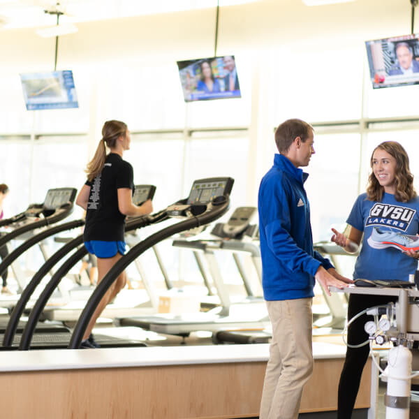 two people talking while one person runs on a treadmill in the Rec Center