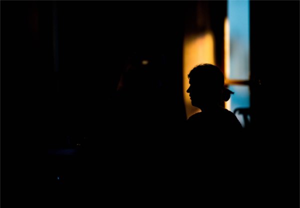  A person is silhouetted in golden light filtering through a window. 