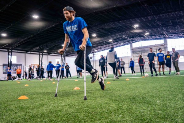  A person uses arm braces while doing soccer drills on green turf. 