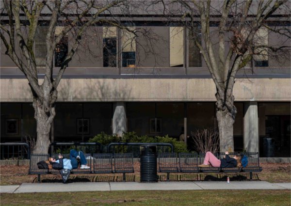  Two college students lay on benches on a university campus.